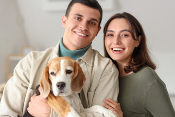 Young couple with cute Beagle dog at home, closeup