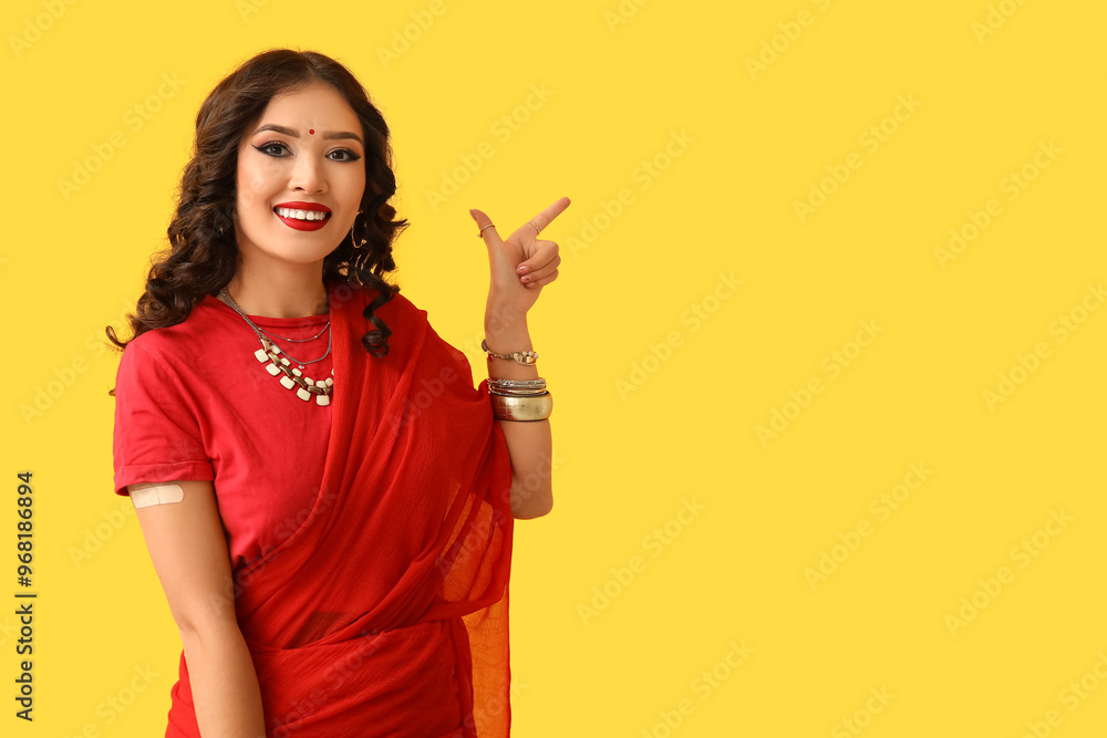 Sticker Beautiful Indian woman in sari with medical patch pointing at something on yellow background