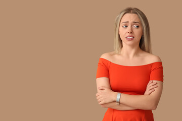 Embarrassed young woman on beige background