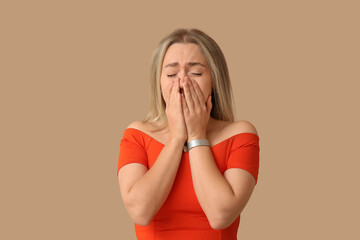 Crying young woman on beige background