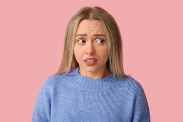 Fototapeta premium Embarrassed young woman on pink background