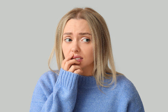 Young woman feeling shame on grey background