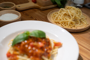 Health food's recipe ingredients of special menu homemade cooking raw spaghetti with tomato sauce and basil of macro photo shooting placing elements on preparing wooden blurred background. Postulate.