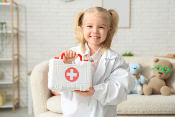 Cute little girl dressed as doctor with first aid kit at home