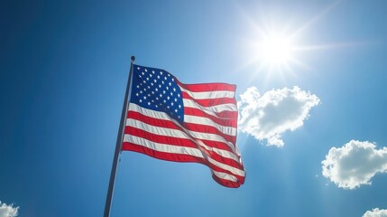 Fototapeta premium A vibrant American flag is gently waving in the breeze under a radiant sun, symbolizing freedom in a clear blue sky