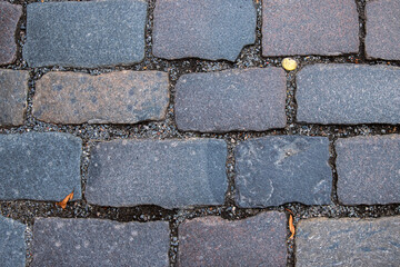 Closeup of weathered granite cobblestone pavement. Detailed image of old stone paving blocks....