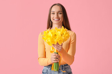 Beautiful young happy woman with bouquet of beautiful narcissus on pink background