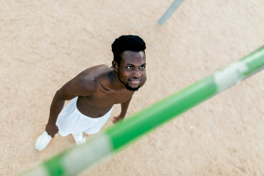 Young man practicing calisthenics on outdoor parallel bars