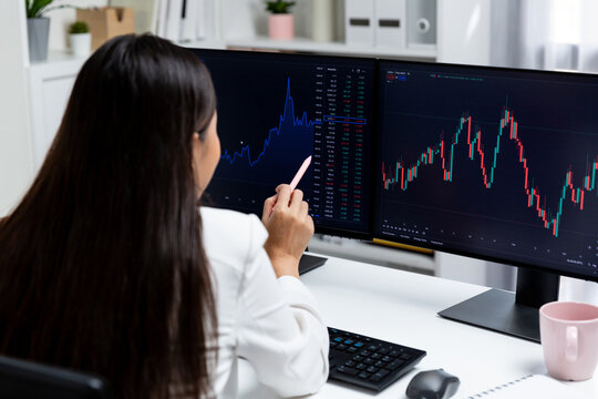 Young beautiful Asian businesswoman pointing with pen in exchange stock market on pc screen at back side view, analyzing profit at modern office, investing high profit valed in wealth. Stratagem.