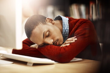 Obraz premium Man, university student and tired with sleep in library by computer with burnout, exhausted or rest for learning. African person, fatigue and dream by pc for education, studying or course at college