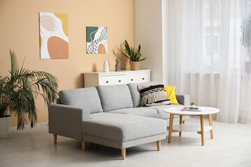 Comfortable sofa, coffee table and picture hanging on beige wall in living room