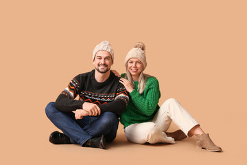 Happy couple in winter clothes hugging on beige background