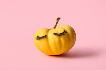 Pumpkin with false eyelashes on pink background