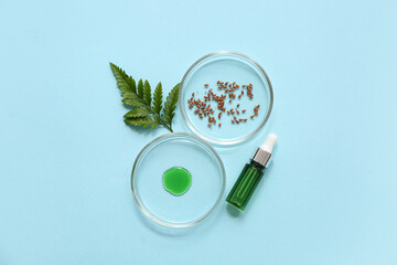 Bottle of oil, Petri dishes with sample and seeds for preparing natural cosmetics on blue background