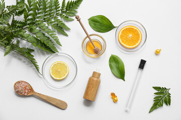 Bottle of oil, Petri dishes with plants and ingredients for preparing natural cosmetics on white background