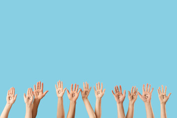 Many hands with word OKTOBERFEST written on their palms against blue background. Octoberfest celebration