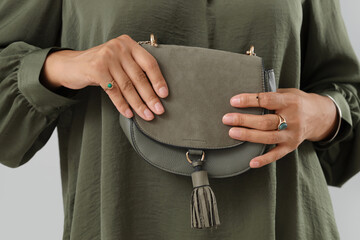 Beautiful young African-American woman with stylish jewellery and bag on grey background, closeup