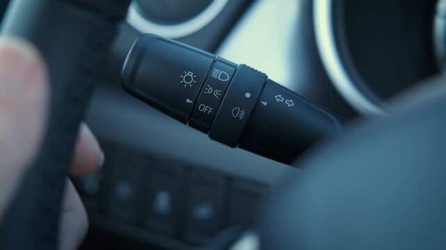 Using a light switch in car. A woman use a light switch controller by the wheel inside the car during driving.