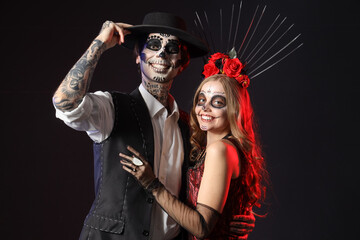 Young happy couple dressed for Mexico's Day of the Dead (El Dia de Muertos) on black background