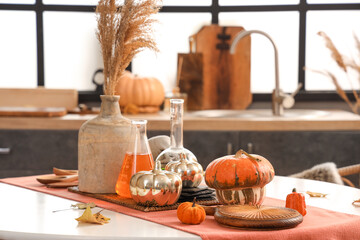 Halloween pumpkins, potions and vase with pampas grass on dining table in kitchen, closeup