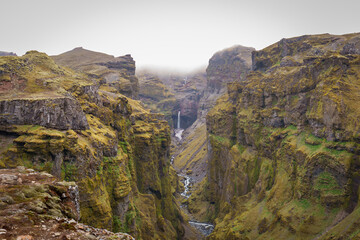 Fototapeta premium Stunning mountains with cascading waterfalls flowing through the lush Múlagljúfur Canyon in Iceland's rugged landscape