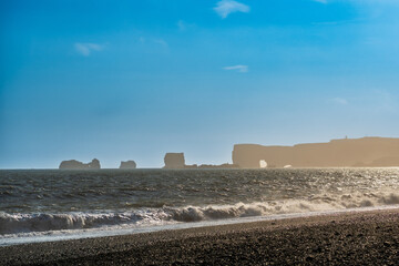 Obraz premium The dramatic Reynisfjara Beach features black volcanic sands and towering basalt sea stacks rising from the wild Atlantic Ocean in Iceland