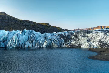 Fototapeten Sólheimajökull Glacier stretches down from the mountains into a serene lake, showcasing Iceland's stunning icy landscape © Ravi
