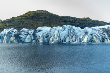 Sólheimajökull Glacier stretches down from the mountains into a serene lake, showcasing Iceland's...