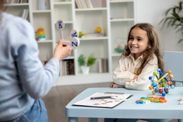 Speech therapist showing letters to a girl while having a training session