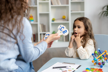 Speech therapist showing letters to a girl while having a training session