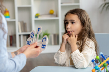 Speech therapist showing letters to a girl while having a training session