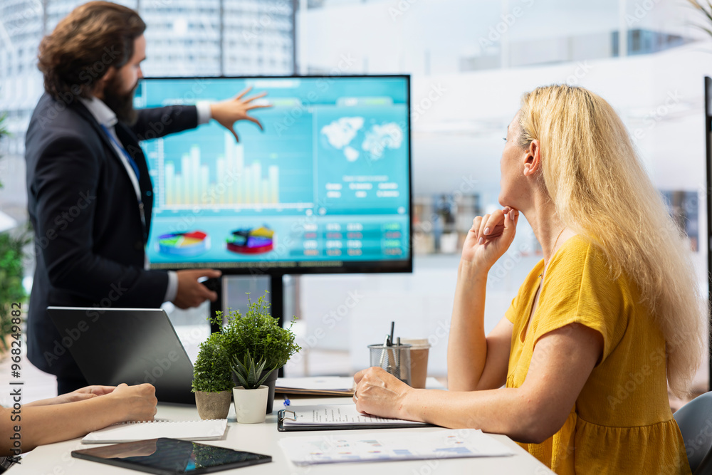 Poster financial adviser presents market analytics to customers using large display, emphasizing data drive
