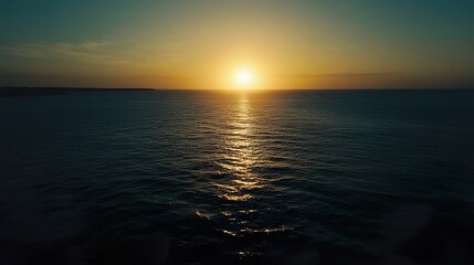Obraz premium The sun is setting over the ocean, casting a warm glow on the water