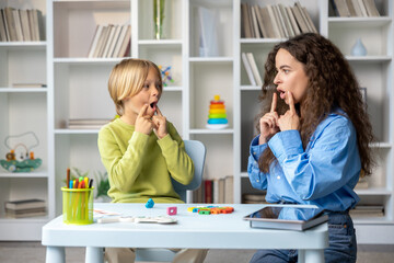 Blonde boy exercising with speech therapist and making efforts