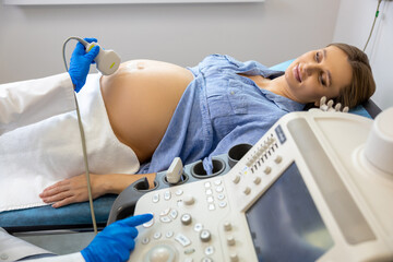 Pregnant woman lying on a couch in clinic while ultrasonography