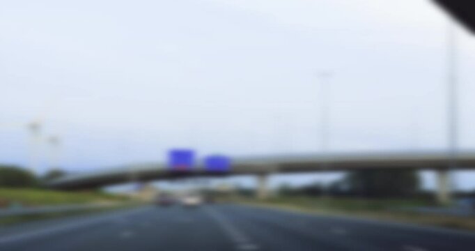 Blurred view of driving under multiple overpasses with several blue road signs, simulating a conceptual representation of a drunk and distorted perspective on the road