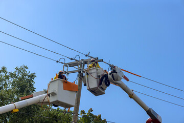 Maintenance of high voltage power lines requires the use of insulated crane basket by an electrician