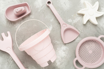 Cute toys for playing with sand on concrete background, top view