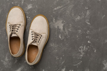 Beige suede shoes on concrete background, top view