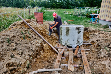 Homeowner uses roller deck to lower one concrete ring on top of another and uses steel crowbar to...