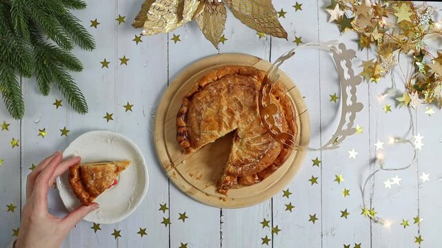 The girl takes out a surprise gift from a piece of royal galette on the table.