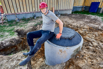 Worker assembled second chamber of septic tank from concrete rings and sat down to rest on manhole cover.