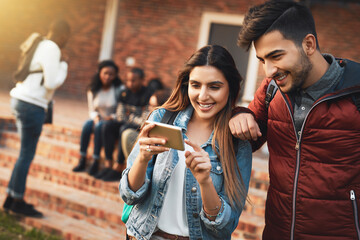 Happy couple, students and watching with phone for social media, communication or streaming at campus. Young, man and woman with smile and backpack on mobile smartphone for online browsing at college