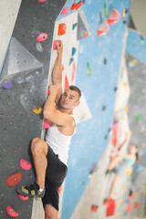 Fototapeta premium Sporty man in doing a difficult wall climb in climbing gym without special climbing equipment
