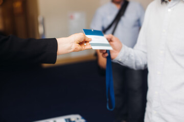 Process of checking in on conference congress forum event, registration desk table, visitors and attendees receiving lanyard with name badge and entry wristband bracelet and register electronic ticket