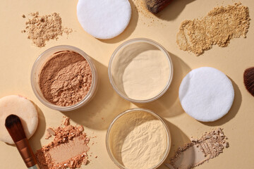 Bottles of face powder, different shades, on a pastel background.