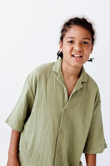 Cheerful young boy in green shirt striking a pose against a minimalist white background