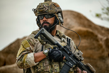 A group of military men in combat gear patrol in the middle of a desert and tropical jungle....