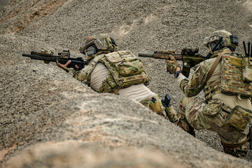Fototapeta premium A group of military men in combat gear patrol in the middle of a desert and tropical jungle. Soldiers in full combat gear in dry weather conditions assemble and march on a mission.