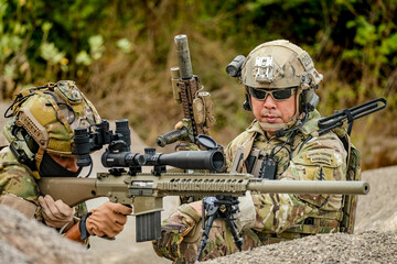 Fototapeta premium A group of military men in combat gear patrol in the middle of a desert and tropical jungle. Soldiers in full combat gear in dry weather conditions assemble and march on a mission.